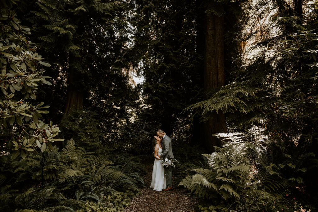 A bride and groom kissing in the forest